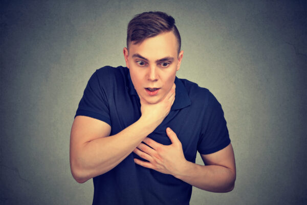 Young man suffering from respiration problems isolated on gray background